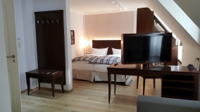 Unsere Zimmer – jedes ganz individuell Blick in ein Hotelzimmer, hinten Bett, vorne TV