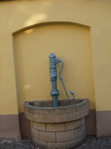 Alter, handbetriebener Brunnen an einer Wand